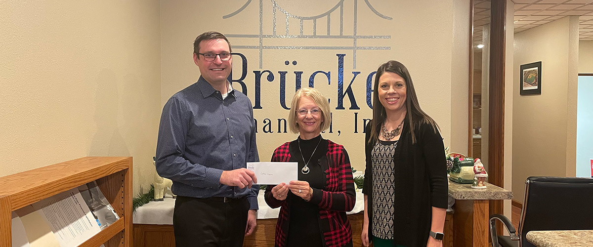 Luke Doedtman and Jenny Kinkelaar giving a check to Beth Lindvahl from Catholic Charities