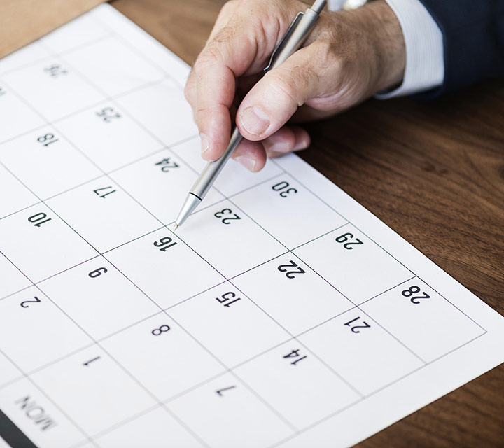 person with pen looking at a calendar