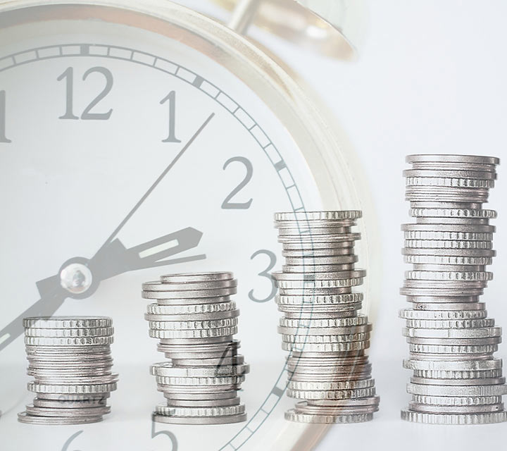 stacked coins in front of a clock